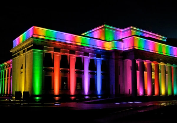 Auckland Museum at night with rainbow lights shining on it.