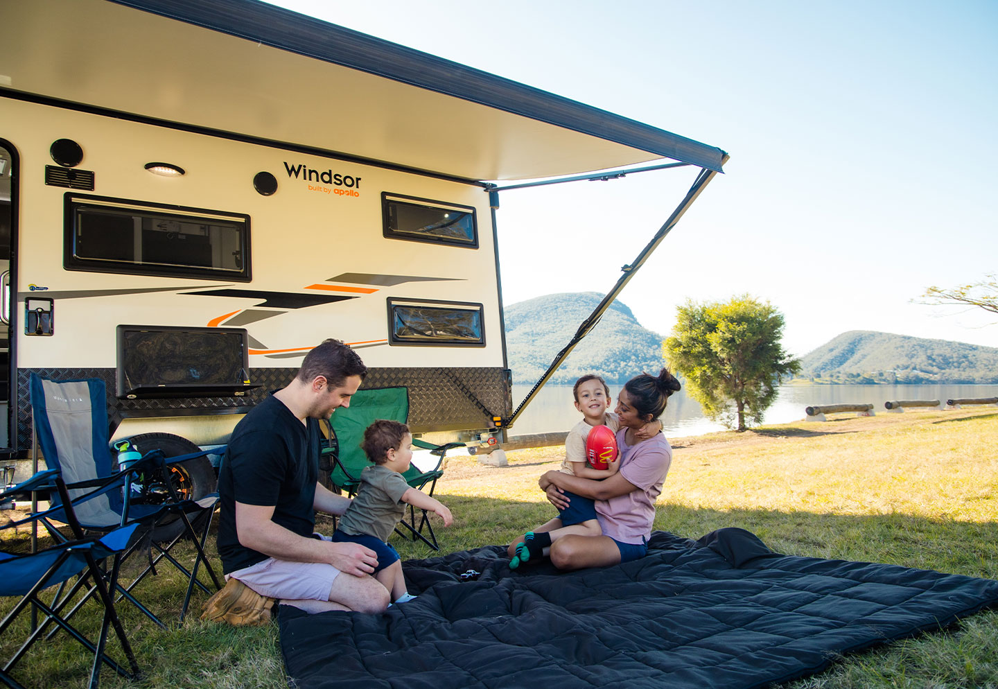 Family outside their caravan, enjoying the outdoors and spending quality time together in a scenic setting