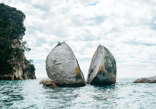 Round rock split in half sitting above the water in the ocean