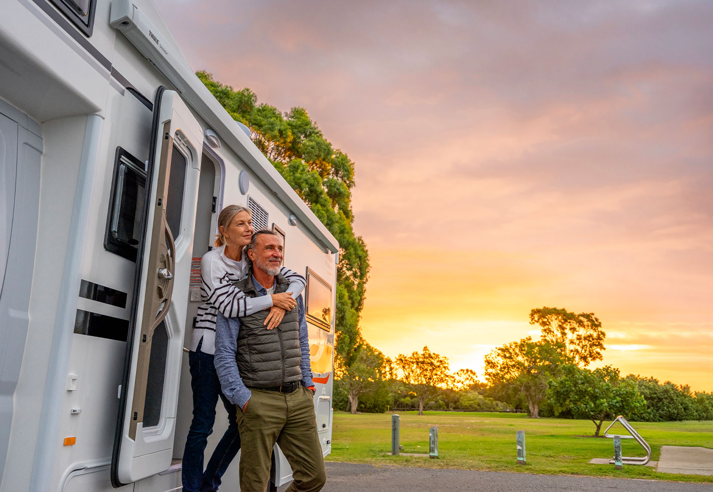 Couple standing outside a motorhome, enjoying the outdoor environment and the motorhome's exterior features.