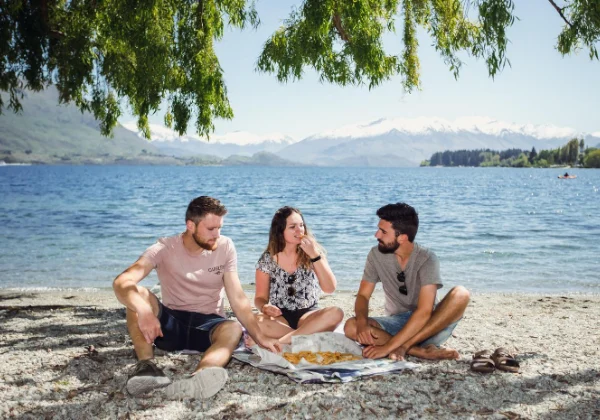 Three friends have a picnic in front of a lake