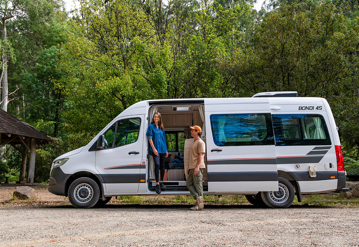 Couple Standing on the outside of their Winnebago Campervan on the Side Sliding Door