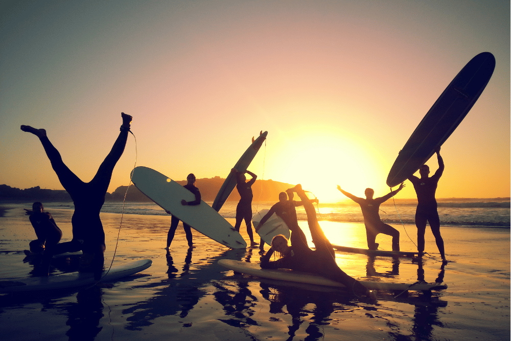Three people holding their surf boards on the beach