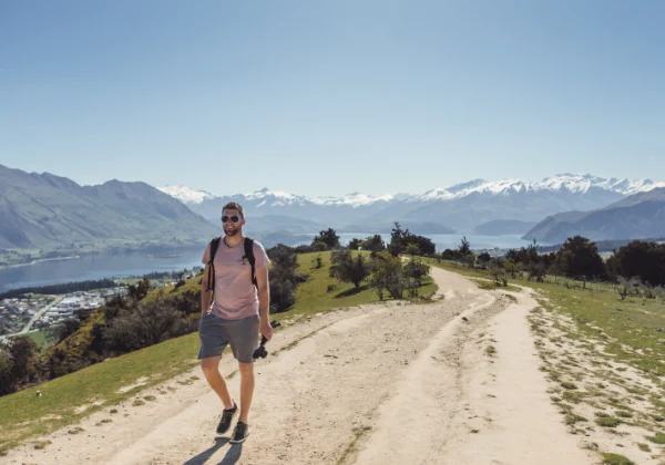 Man on a scenic walk with snowy mountains and a lake