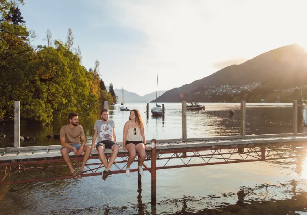Three people sitting on a wharf