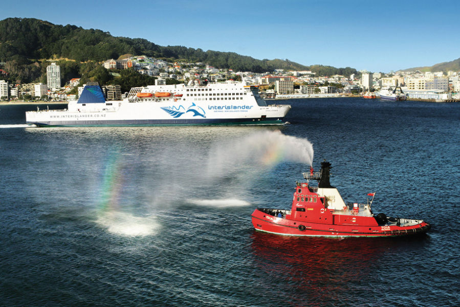 Ferry leaving Wellington with a tug boat spraying water nearby