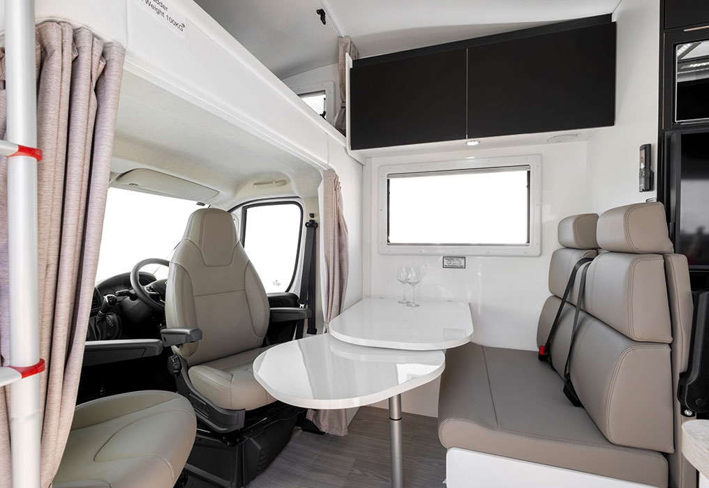 Interior featuring a dinette, slide-out bed, and over-cab bed, highlighting versatile and space-efficient sleeping arrangements.