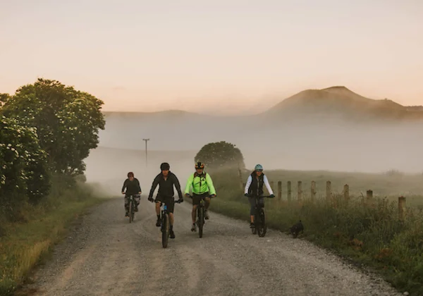Cyclists on a gravel road with fog covered mountains in the background