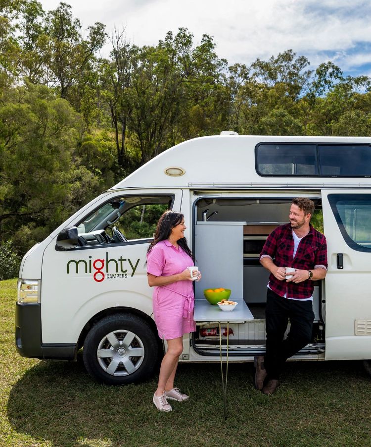 person jumping next to campervan