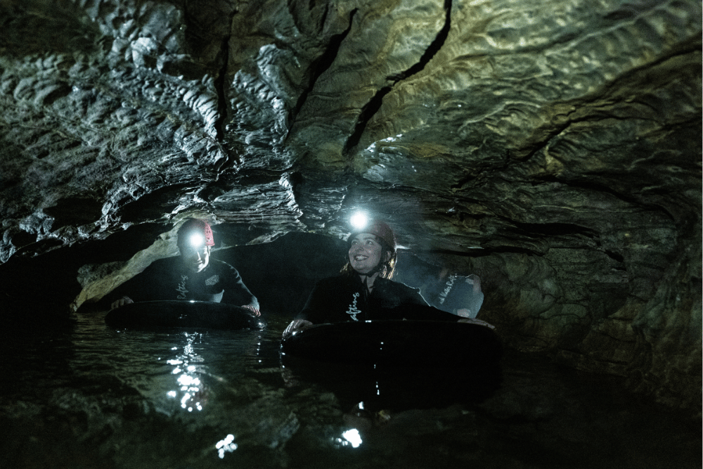 3 people in a cave black water rafting