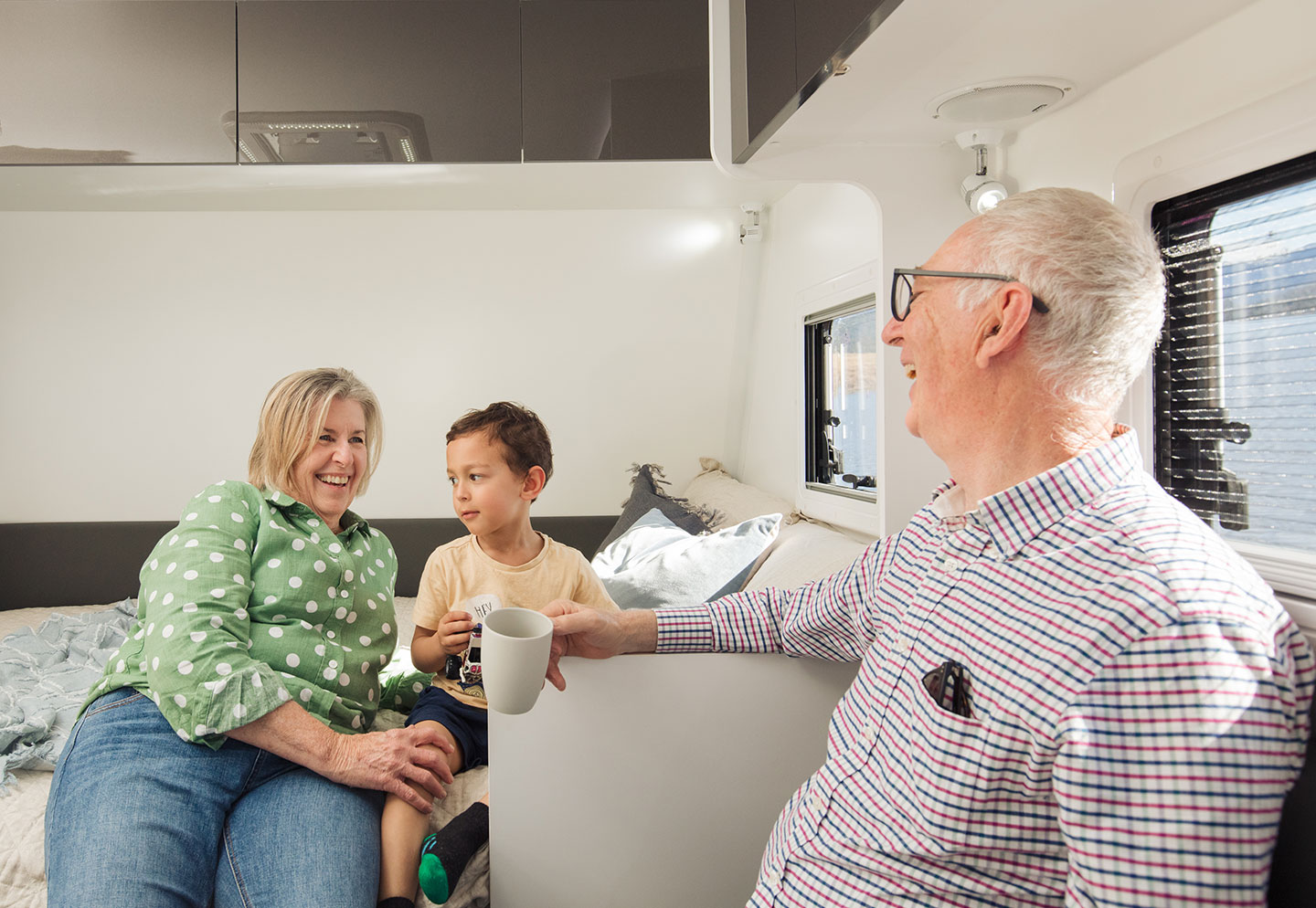 Grandparents inside a caravan with their grandchild, spending time together and enjoying the cozy interior