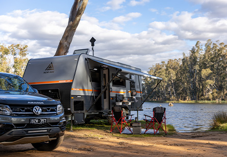 New Age Caravan behind a Black Ute, camping setup in front of a lake.