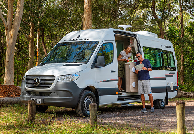 Couple at the side of a Winnebago campervan looking at a map.