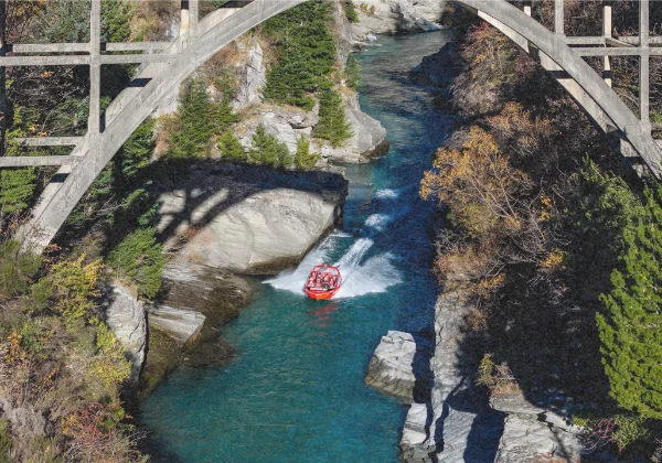 Aerial view of jet boat racing down a narrow river
