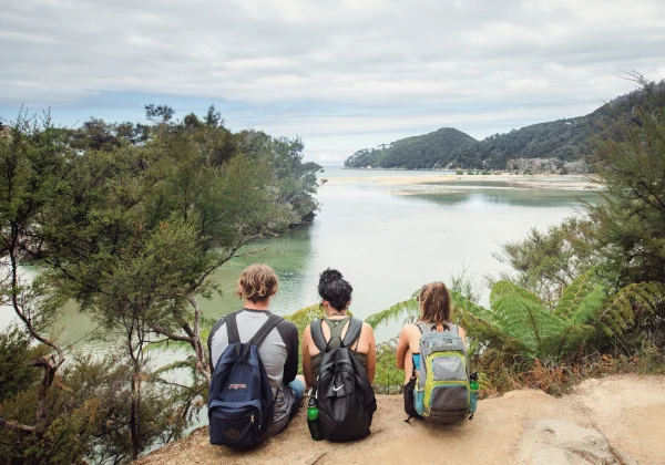 Three people sitting enjoying the view of water and trees